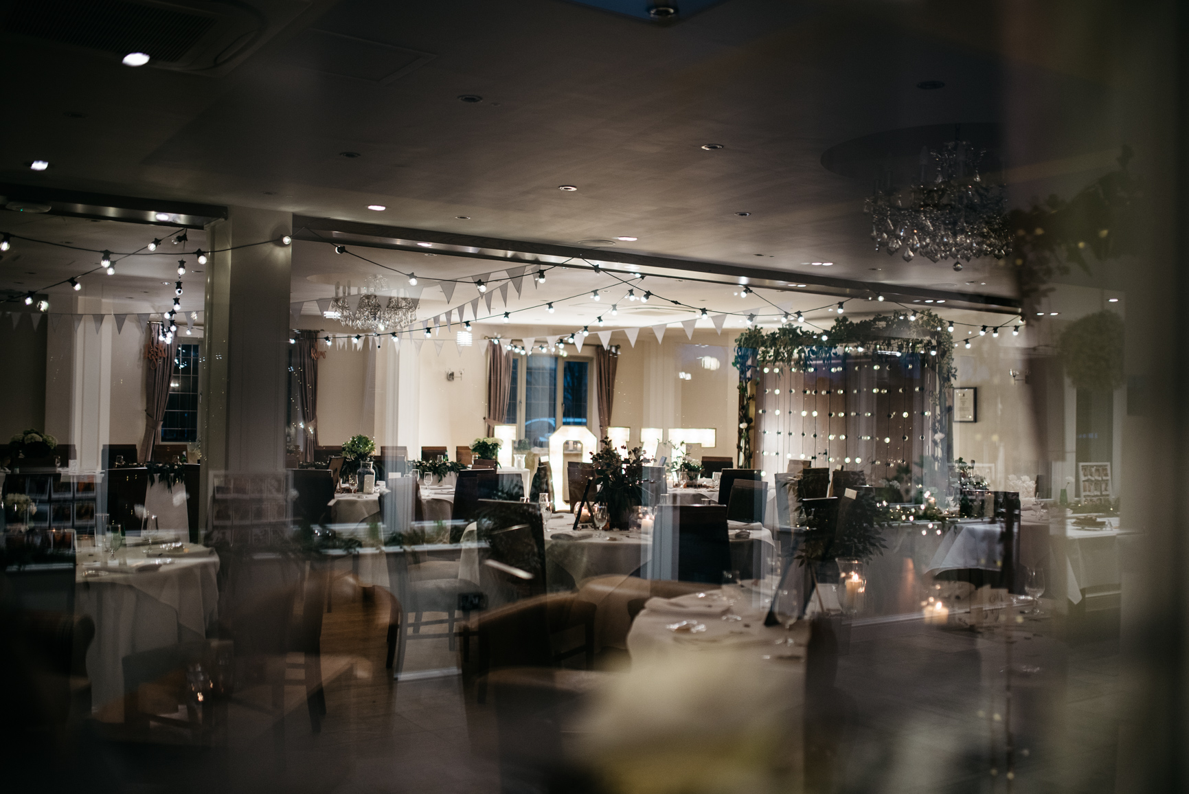 large room with chairs and tables decorated with bunting and fairy lights