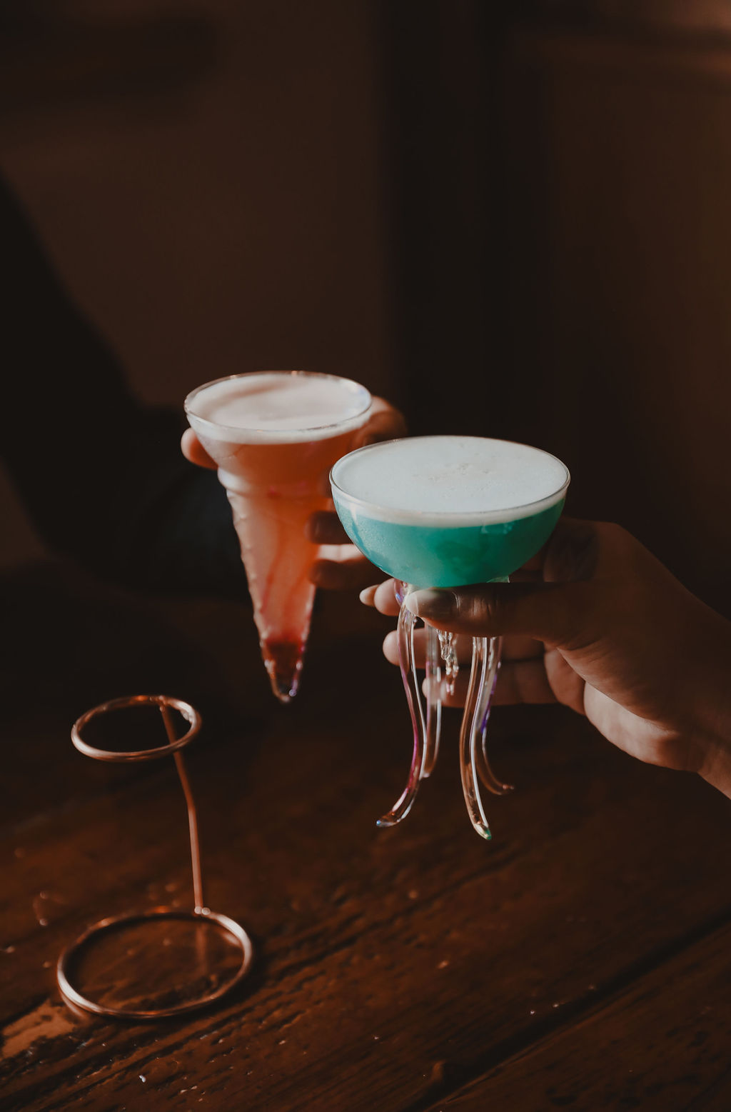 two people tapping cocktail glasses together