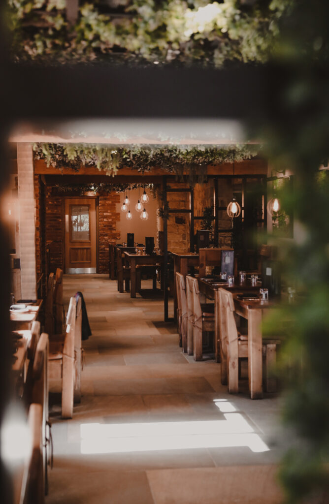 long restaurant with greenery around and large wooden chairs